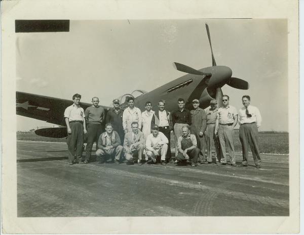 A picture of Harvey Yearke, standing with a group by a P-40